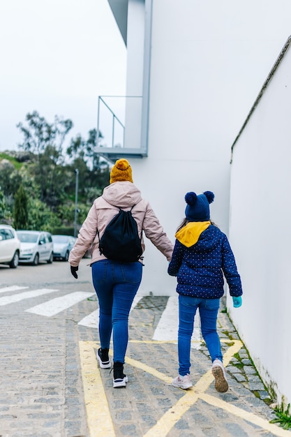 Zdjęcie matka i córka, trzymając się za ręce i spacerując po ulicy w zimowe ubrania