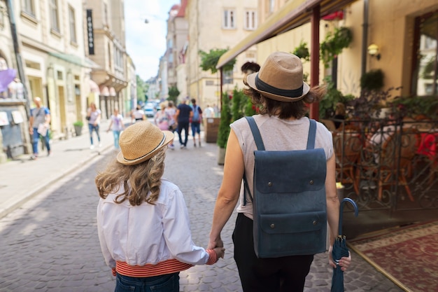 Matka i córka, trzymając się za ręce, spacery w starym mieście turystycznym