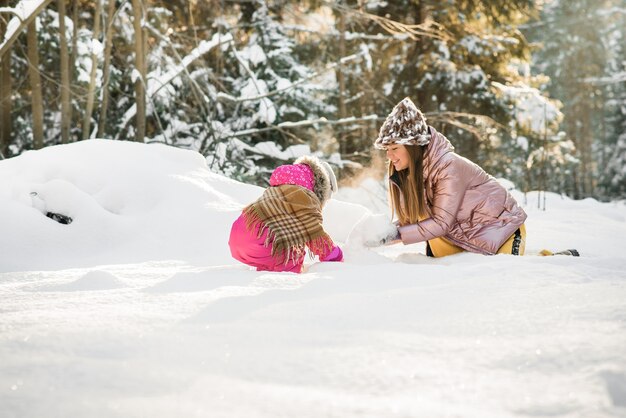 Matka i córka zawinięte w szalik w śnieżnym zimowym lesie. podróże i rekreacja