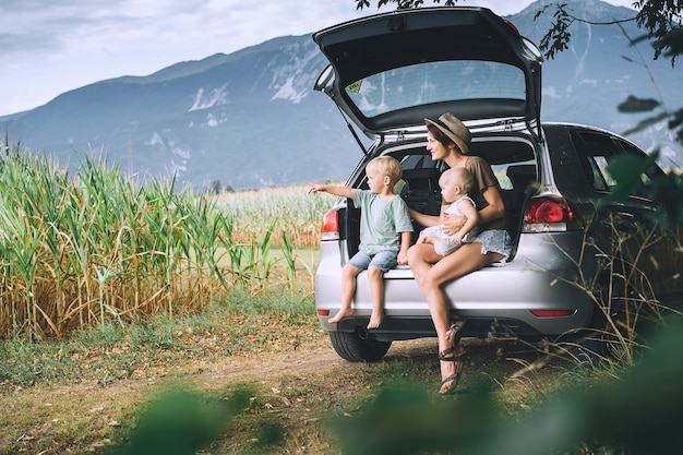 Matka I Dzieci Siedzą W Otwartym Bagażniku Samochodu I Obserwują Przyrodę Rodzina W Podróży