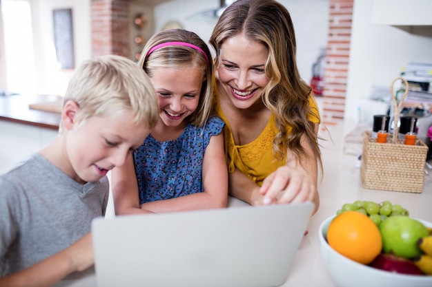 Matka i dzieci za pomocą laptopa w kuchni