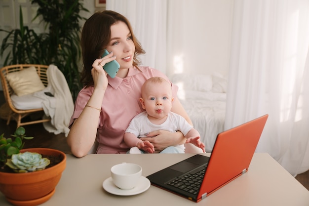 Matka i dziecko w domowym biurze z laptopem i telefonem