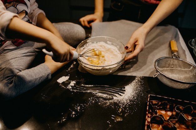 Zdjęcie matka i dziewczynka mieszając mąkę z jajkami, robiąc ciasto na ciasteczka