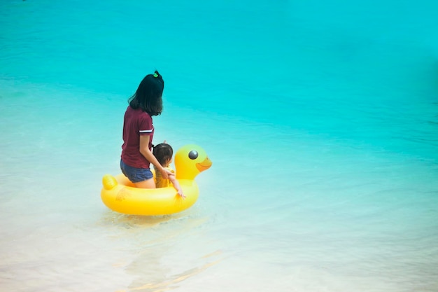 Matka i dziewczynka są w gumowym pierścieniu żółtej kaczki na plaży