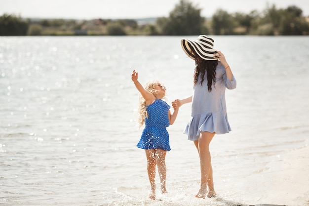 Matka I Jej Mała Córka Zabawy Na Wybrzeżu. Młoda ładna Mama I Jej Dziecko Bawiące Się W Pobliżu Wody