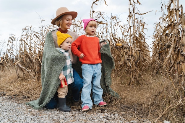Matka i małe dzieci bawiące się razem przed rolniczym polem kukurydzy Rodzina z dziećmi zabawy Tradycje Święta Dziękczynienia i koncepcja Halloween Organiczne ogrodnictwo ekologia zrównoważony styl życia