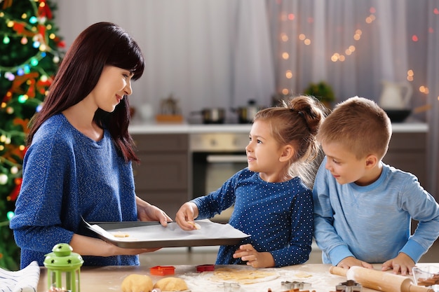 Matka i małe dzieci robią świąteczne ciasteczka w kuchni