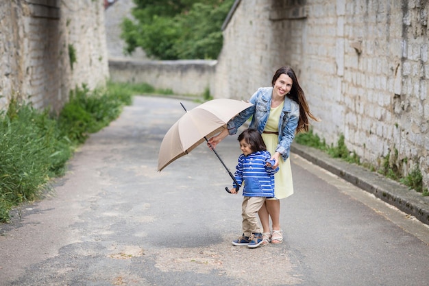 Matka i mały wschodni przystojny chłopiec bawiący się parasolem na zewnątrz