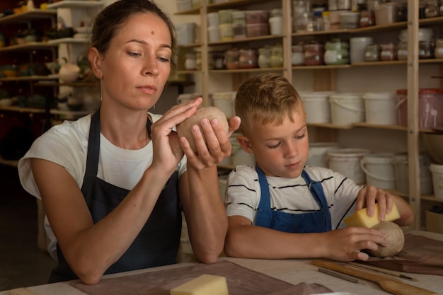 Matka i nastoletni syn spędzają razem czas i rzeźbią z gliny w szkole garncarskiej