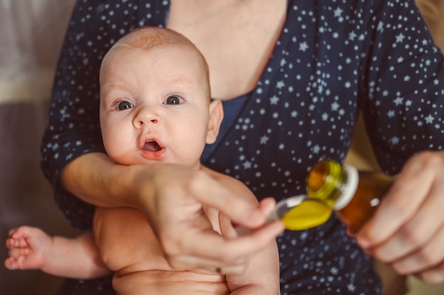 Matka i noworodek zabawny płacz emocjonalny niemowlę nagi chłopiec bierze płynne leki lub