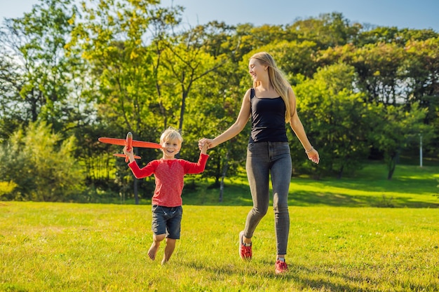 Matka i syn bawią się dużym modelem samolocikiem w parku.