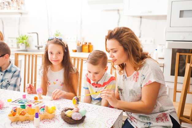 Matka i syn przygotowują się do Wielkanocy, ciesząc się razem. Mama i dzieci malują pisanki przy stole