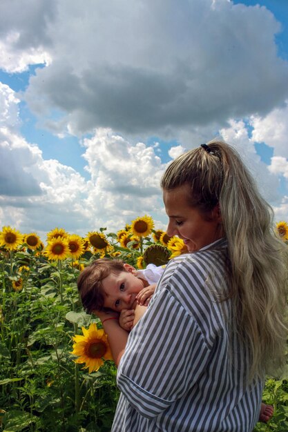 Zdjęcie matka i syn stoją obok kwiatu na tle nieba