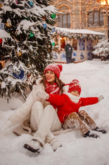 Matka i syn w ciepłych ubraniach bawią się zimą na śnieżnym jarmarku noworocznym na Placu Czerwonym w Moskwie