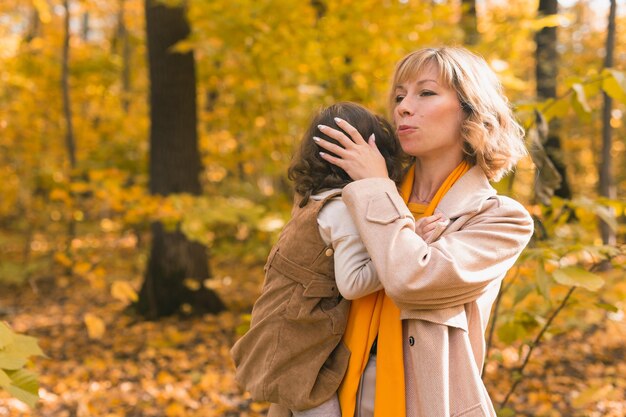 Matka koi płaczącą blond córkę mama trzyma w ramionach smutek dziecko w jesiennej przyrodzie