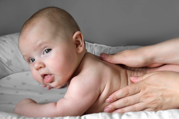 Matka masująca małe dziecko Zbliżenie Mama masuje niemowlę Dziecko Zapobieganie drżeniem Kobiece dłonie Delikatnie masuje noworodka Nagie ciało Rozmazuje kremem Koncepcja pielęgnacji ciała