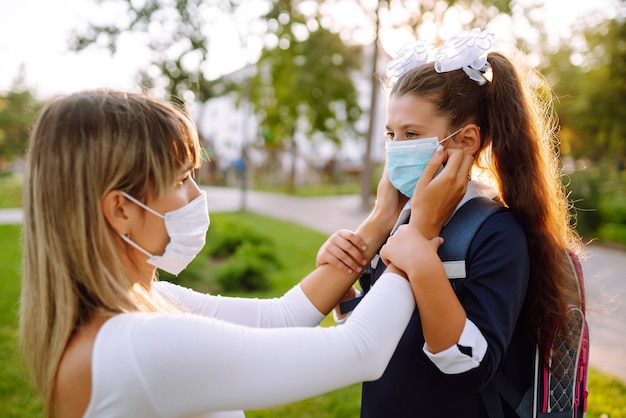 Matka nakłada na uczennicę ochronną sterylną maskę. Covid19 Kwarantanna.