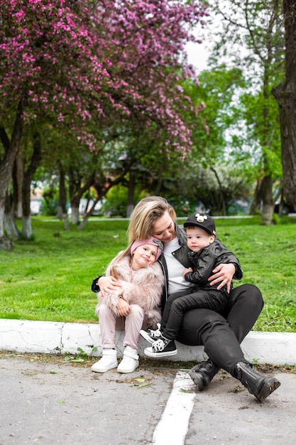Matka niosąca syna i córkę podczas zabawy w parku