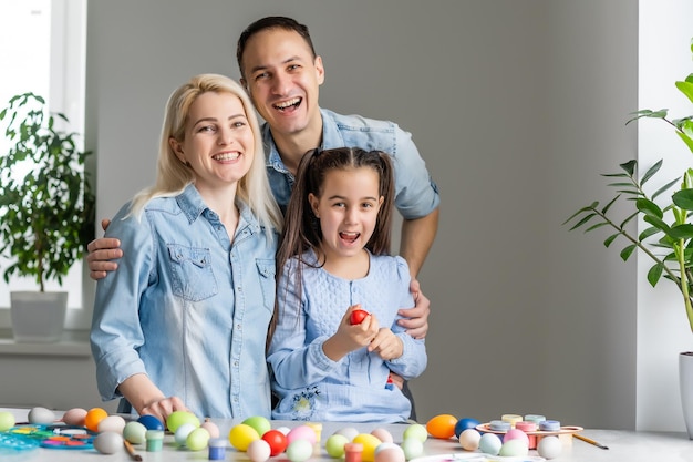 Matka, ojciec i córka malują jajka. Szczęśliwa rodzina przygotowuje się do Wielkanocy.