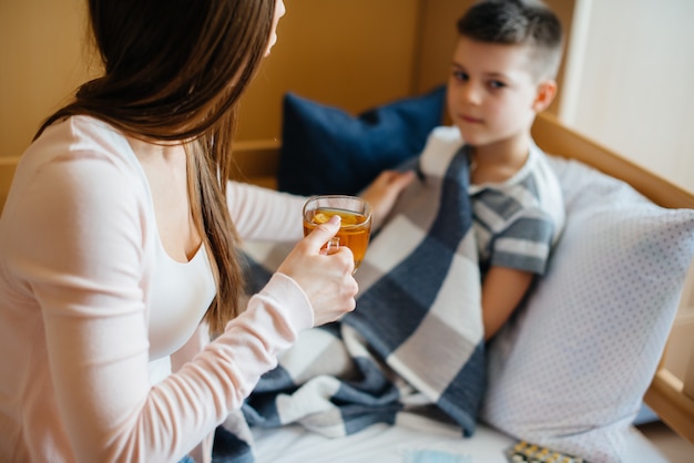 Matka podaje swojemu dziecku gorącą herbatę z cytryną podczas choroby i wirusa. Medycyna i opieka