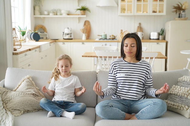 Matka przybrana córka ćwiczy jogę siedząc na kanapie w domu Przyjęcie dziecka w zdrowym stylu życia