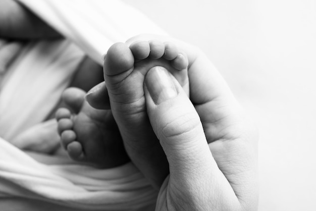Matka robi masaż na jej stopie dziecka Zbliżenie stóp dziecka w rękach matki Zapobieganie rozwojowi płaskostopia dysplazja napięcia mięśni Rodzinna miłość opieki koncepcje zdrowotne Czarno-białe makro