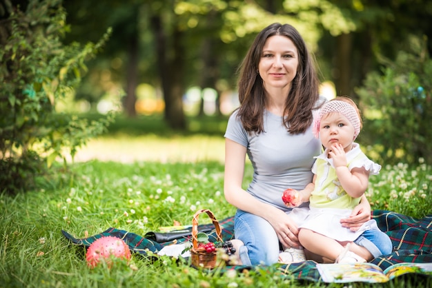 Matka siedzi na trawie z małą córeczką