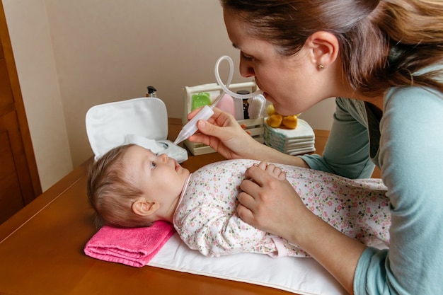 Matka używa aspiratora do nosa do czyszczenia nosa dziecka
