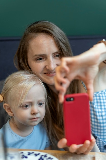 Matka z córeczką robi selfie Młoda kobieta i dziewczynka patrzą na telefon Pionowa ramka