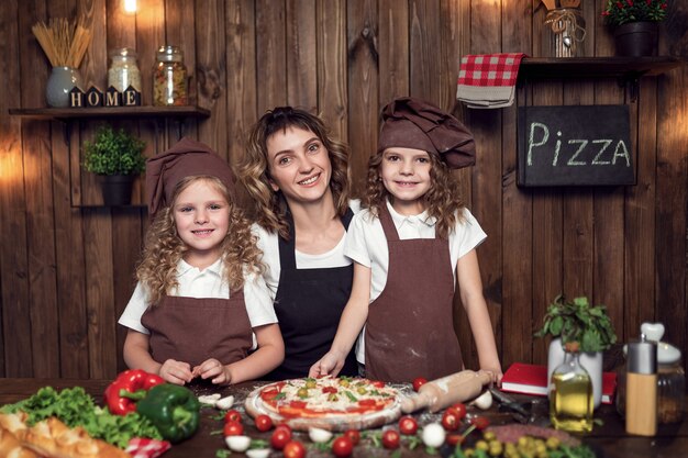 Matka z córkami gotuje pizzę w kuchni