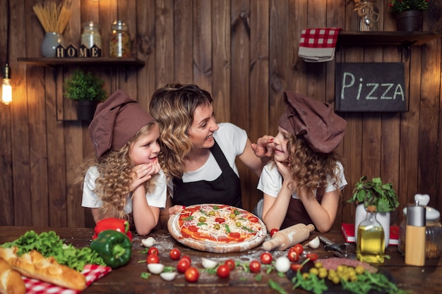 Zdjęcie matka z córkami gotuje pizzę w kuchni