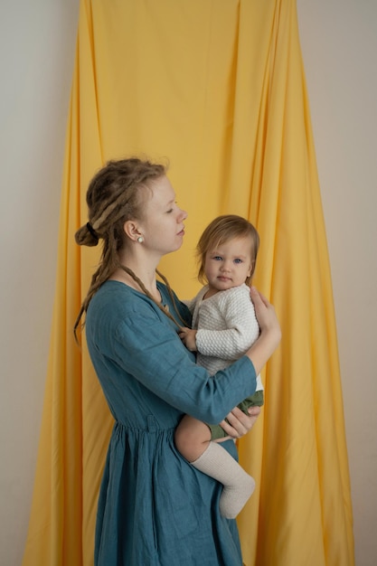 Matka z dredami z dzieckiem w ramionach na żółtym tle tkaniny Zbliżenie