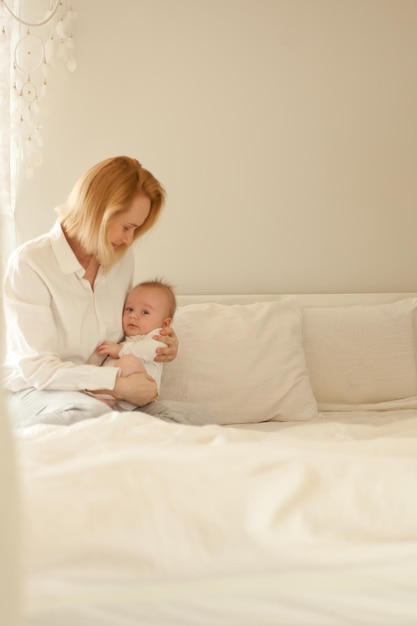 Matka z dzieckiem w białej sypialni mały chłopczyk z mamą macierzyństwo i dzieciństwo