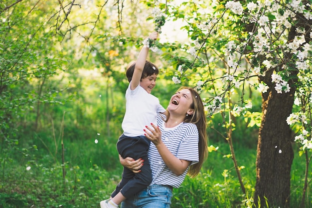 Matka z małym synkiem w wiosennym ogrodzie podczas złotej godziny Mama i syn są aktywni w naturze Rodzinne spacery w wiosennym ogrodzie Szczęśliwego dnia matki