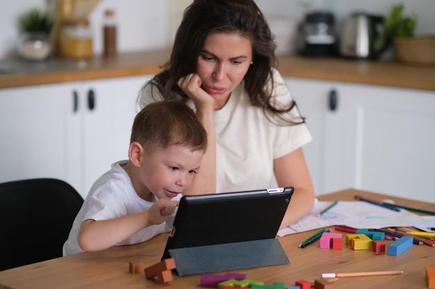 Matka z młodym chłopcem za pomocą cyfrowego tabletuszczęśliwa mama i dziecko grają w edukacyjne gry online na tablecie