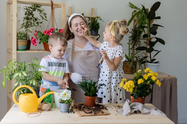 Matka z synem i córką na czczo lub przesadzają kwiaty w pomieszczeniach