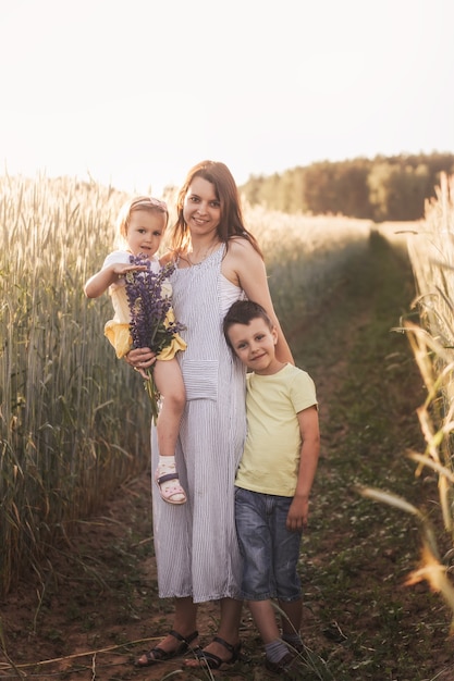 Matka z synem i córką z kwiatami latem na polu