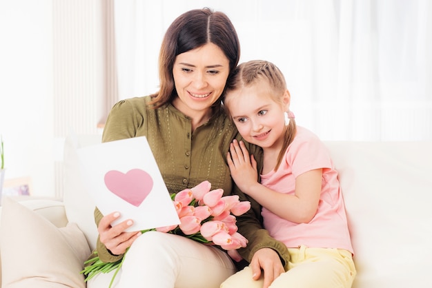 Matka z zainteresowaniem czyta pocztówkę z życzeniami od córki w Dzień Matki