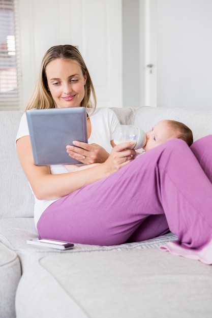 Matka Za Pomocą Cyfrowego Tabletu Podczas Karmienia Dziecka Butelką Mleka