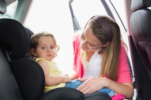 Matka zabezpiecza swoje dziecko w foteliku samochodowym