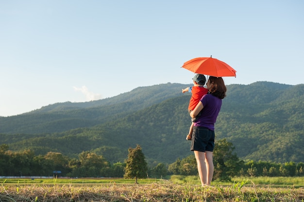 Matki i syna mienia parasol outdoors przy zmierzchem