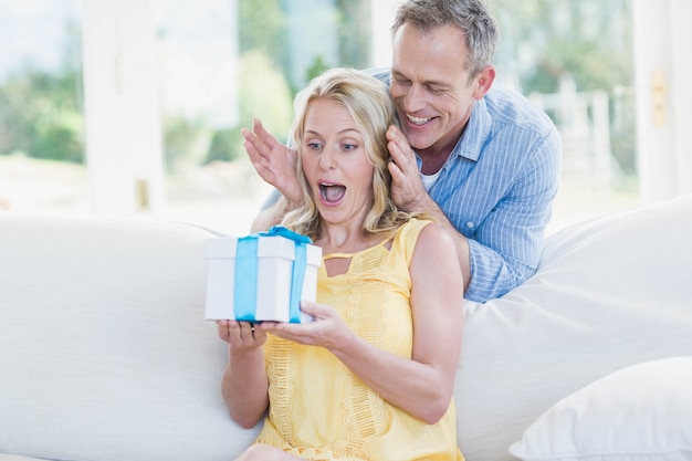 Mąż zaskakująca żona z prezentem w salonie