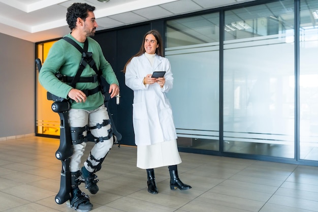 Mechaniczny egzoszkielet kobieta lekarz fizjoterapeutka chodząca z osobą niepełnosprawną z pomocą fizjoterapii szkieletowej robota w nowoczesnym szpitalu futurystyczna fizjoterapia