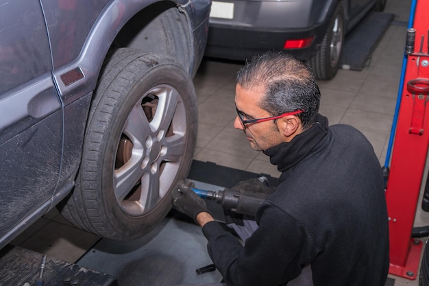 Mechanik dostosowujący koło samochodowe w warsztacie samochodowym