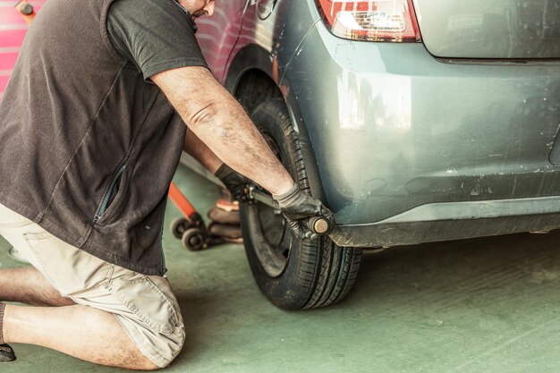 Mechanik kucający podczas montażu koła w samochodzie w garażu