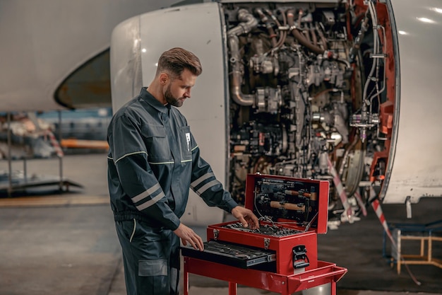 Mechanik męskich linii lotniczych korzystający ze skrzynki narzędziowej w hangarze