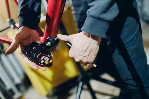 Mechanik montuje niestandardowy rower z przekładnią zębatą pedału w warsztacie