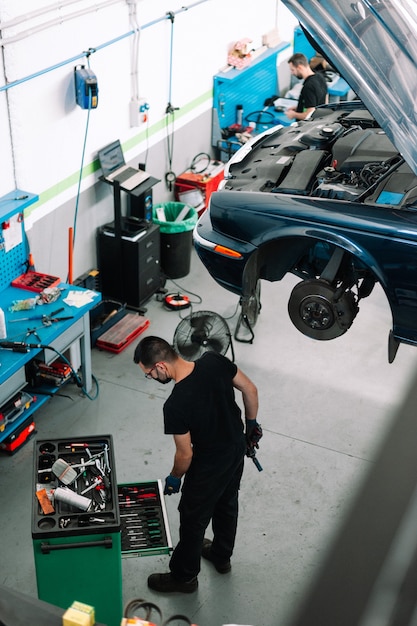 Zdjęcie mechanik naprawiający samochód w warsztacie samochodowym