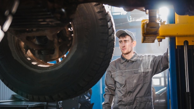 Mechanik podnosi SUV w garażu samochodowym koło serwisowe z bliska poziomo