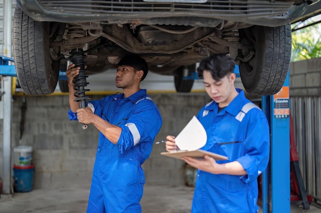 Mechanik pokazuje raport azjatyckiemu współpracownikowi w garażu Mechanik i jego syn omawiają wykonane naprawy pojazdu Zmiana biznesu samochodowego